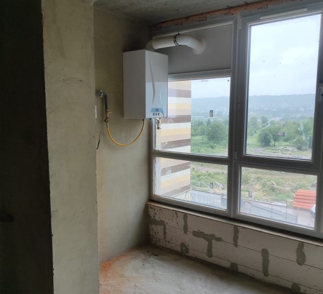 Unfinished room with a wall-mounted white gas boiler and vent pipe, yellow gas line looping to it, near a large window with a green landscape outside.